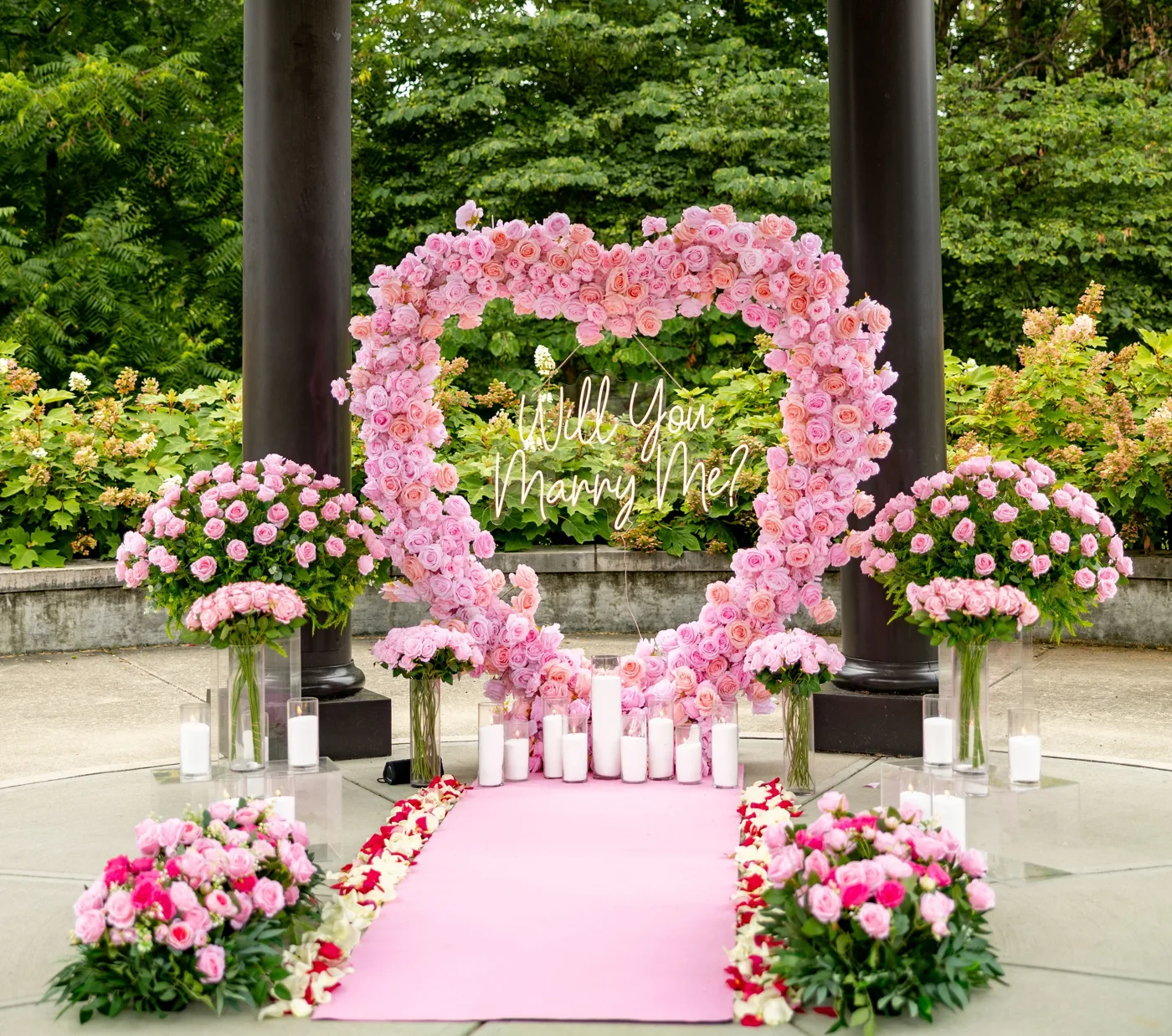 Pink rose heart arch with Will You Marry Me neon sign